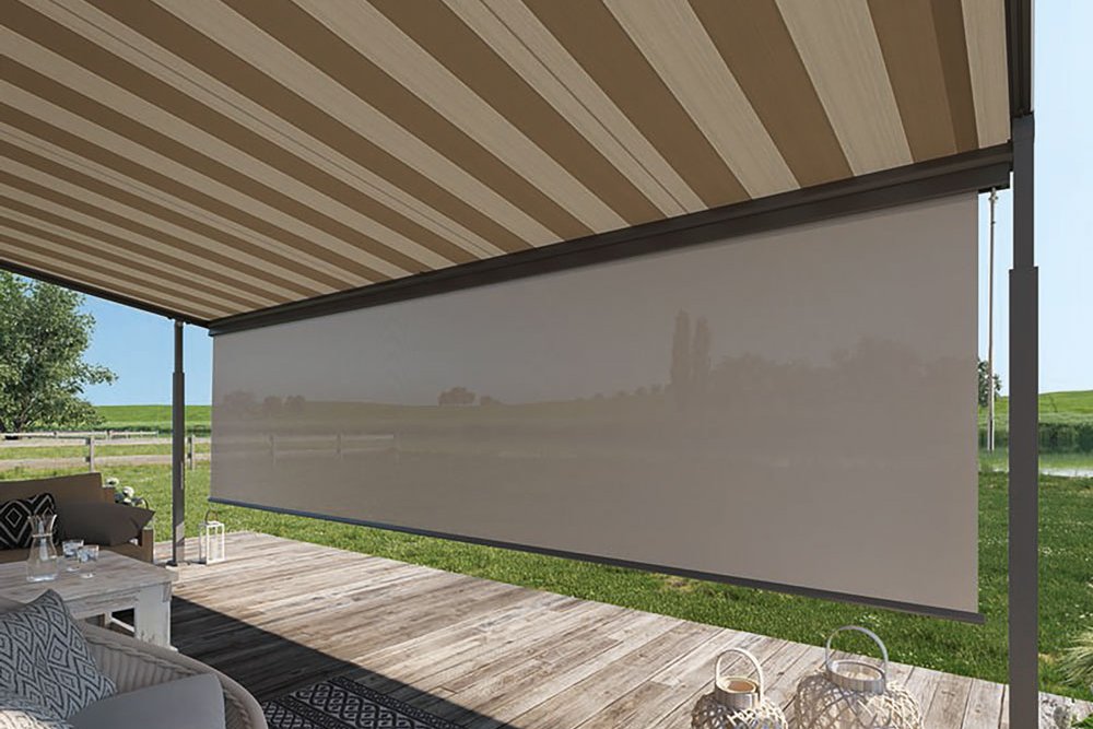 A striped retractable awning above a wooden terrace with a scenic green backdrop. A striped retractable awning above a wooden terrace with a scenic green backdrop.