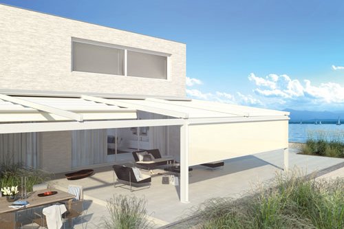 A modern terrace with a white overhead structure and a view of the water, featuring seating and a dining area. A modern terrace with a white overhead structure and a view of the water, featuring seating and a dining area.
