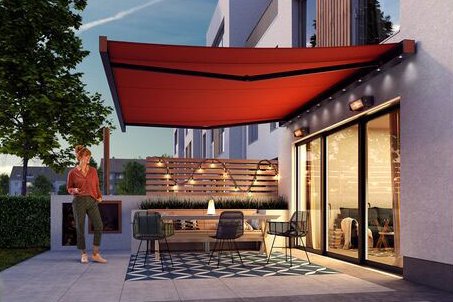 A modern patio with a red awning, greenery, and contemporary architecture in a twilight setting. A modern patio with a red awning, greenery, and contemporary architecture in a twilight setting.