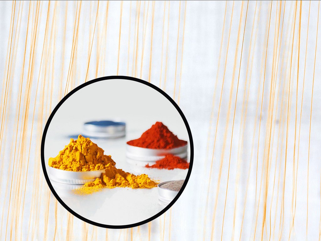Piles of yellow and red powders inside circular containers on a light background. Piles of yellow and red powders inside circular containers on a light background.