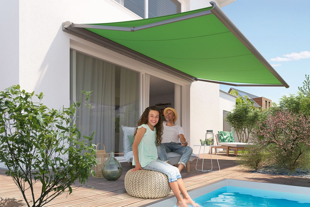 Two people relaxing by a swimming pool under a green awning, with surrounding plants and a wooden deck. Two people relaxing by a swimming pool under a green awning, with surrounding plants and a wooden deck.